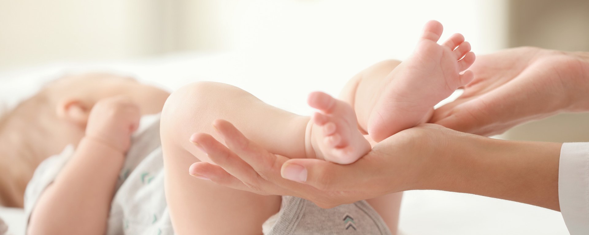 Ein Baby liegt auf einer Wickelkommode. Die Mutter hält die Füße in der Hand.