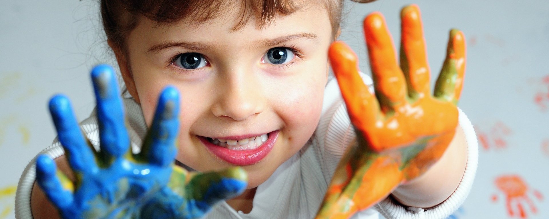 Nahaufnahme eines Kindes mit einer blauen und orangen angemalten Hand.